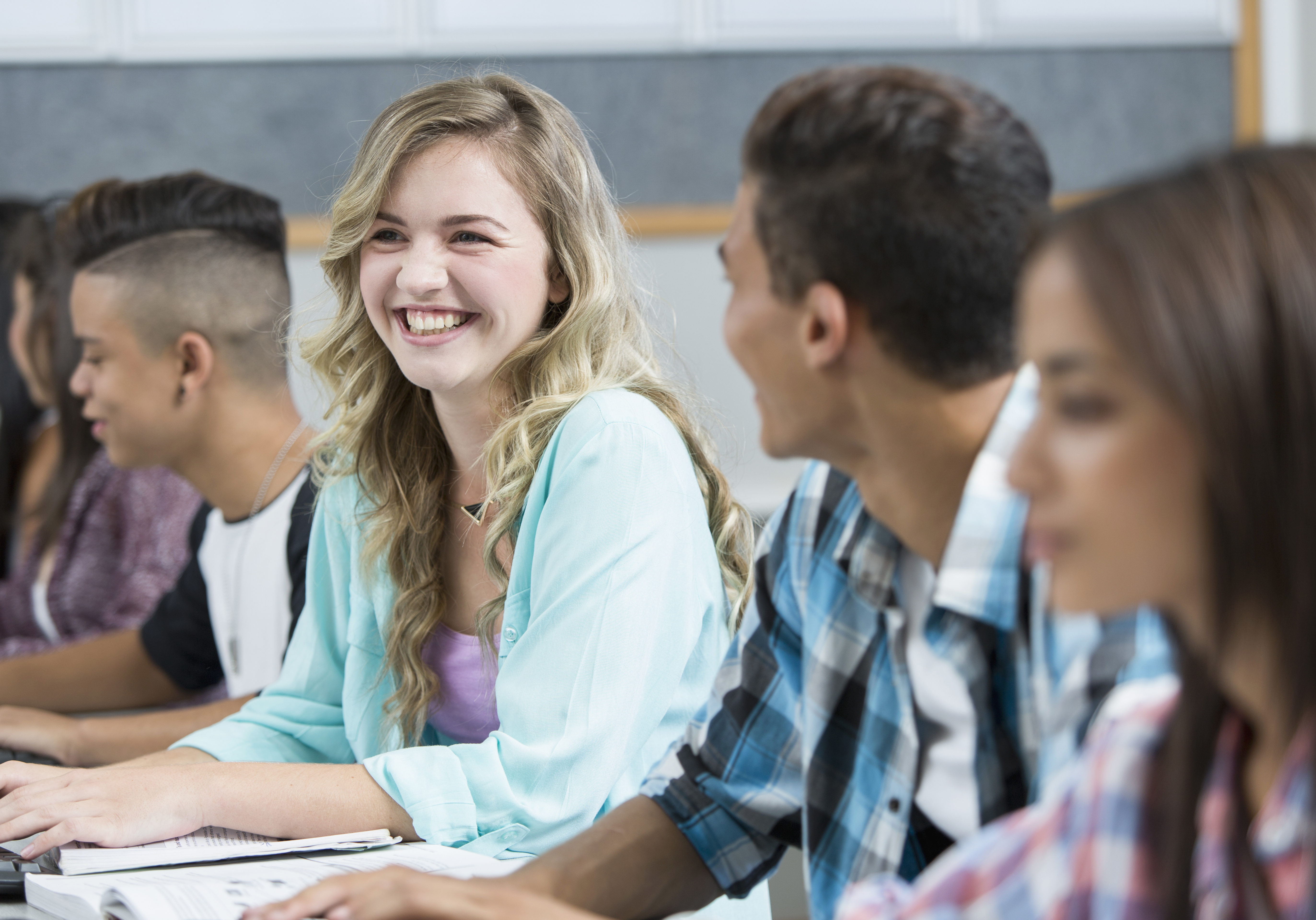 Row of teenage high school students smiling in computer class