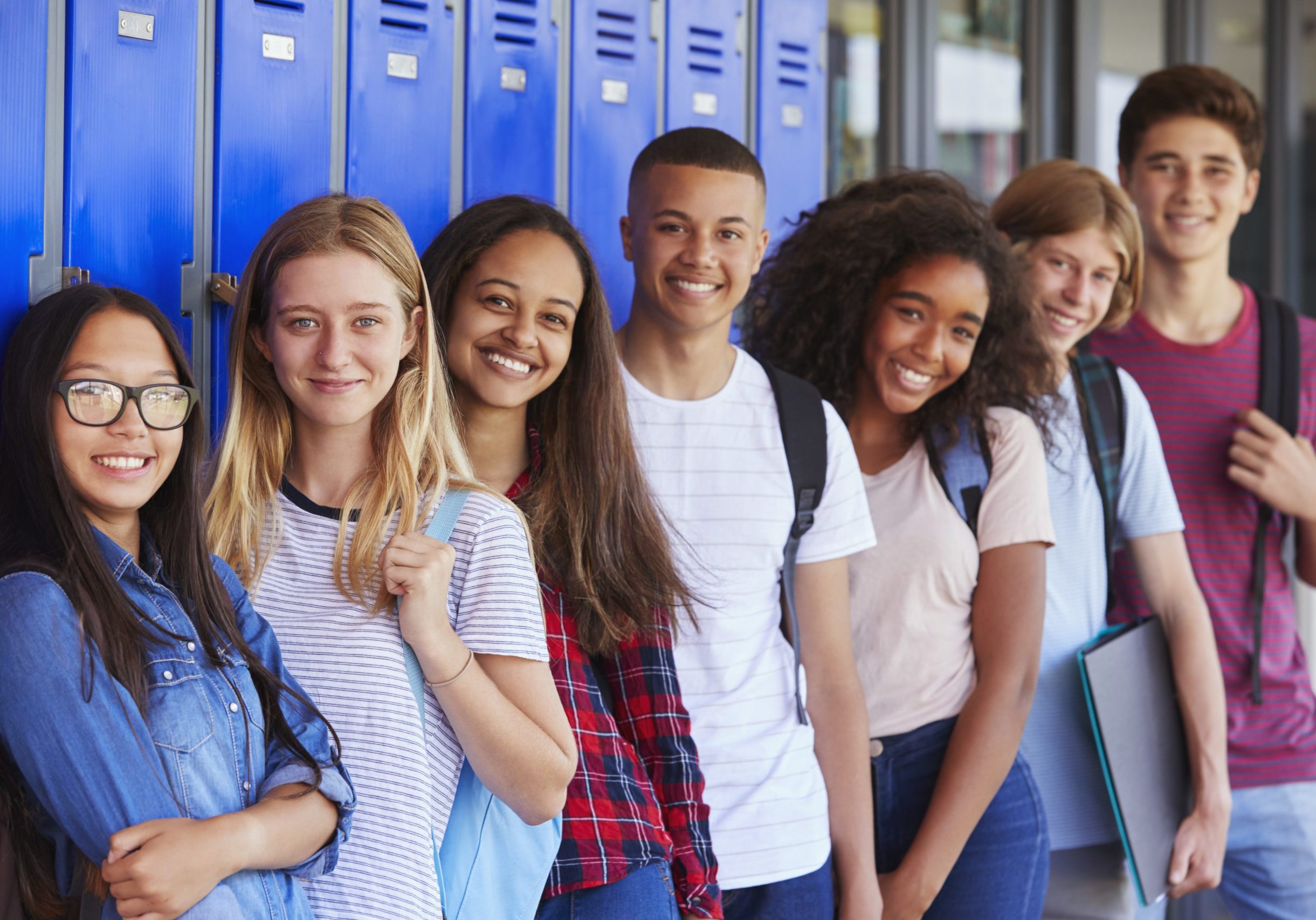 Teenage school kids smiling to camera in school corridor